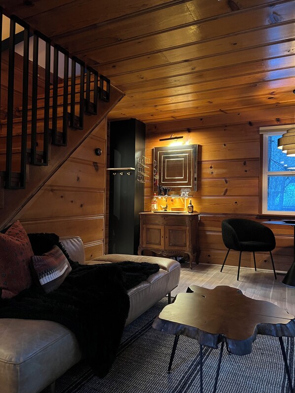 L’intérieur chaleureux d’un chalet avec un escalier, des murs en bois, un coin repas et une fenêtre offrant une vue agréable.