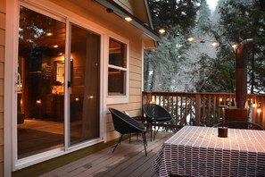 Une terrasse extérieure couverte, avec une table et des chaises, une terrasse en bois et une vue sur les arbres.