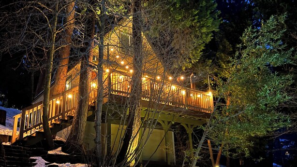 Ein Haus mit einer Holzterrasse und Treppe, umgeben von Bäumen.