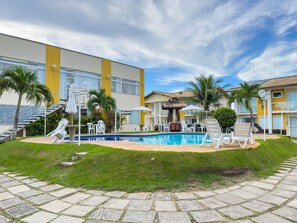 Un hôtel doté d’une piscine, d’un espace extérieur aménagé et de palmiers.