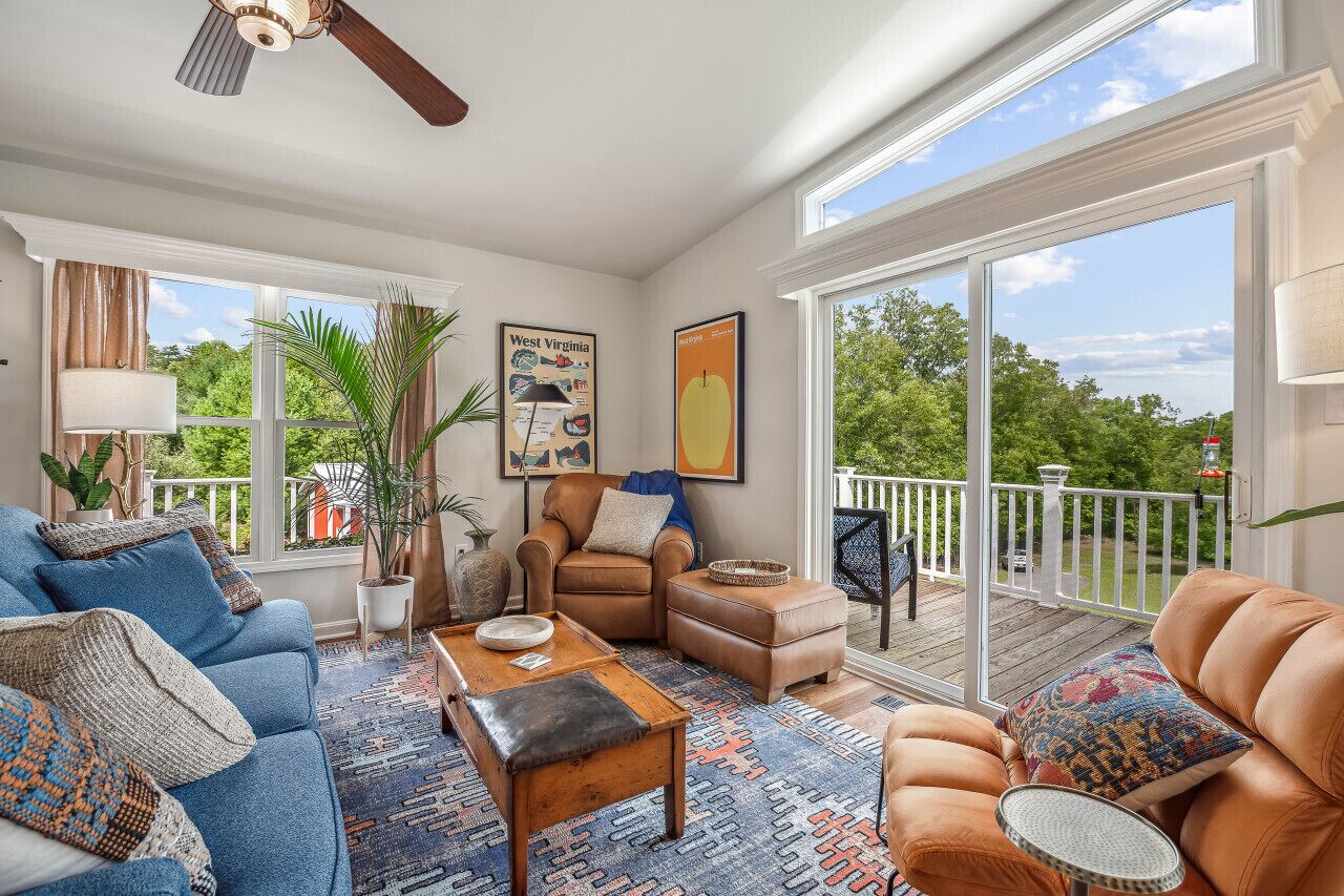 A spacious living room with a large window, a ceiling fan, a sofa, a coffee table, and a chair.