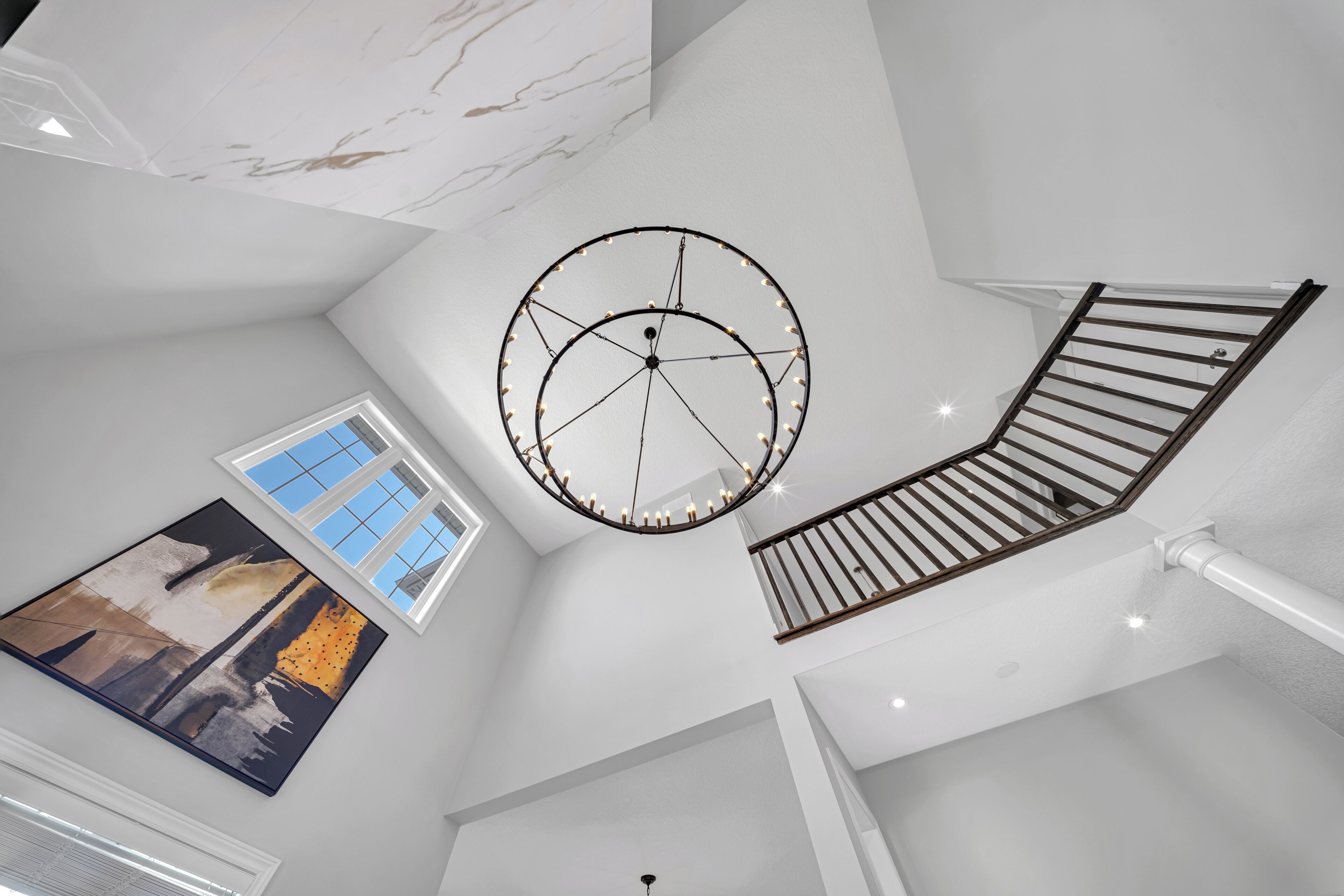 A modern interior with a circular light fixture, a staircase, and a large window.