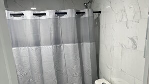 Kylpyhuone, jossa on suihkuverho, wc ja pesuallas.