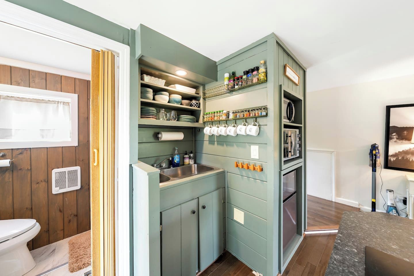 A compact kitchen with built-in shelves, a sink, and a microwave.