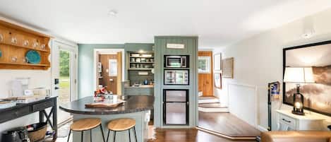 Een moderne keuken met een centraal eiland, barkrukken en een zithoek met een bank.
