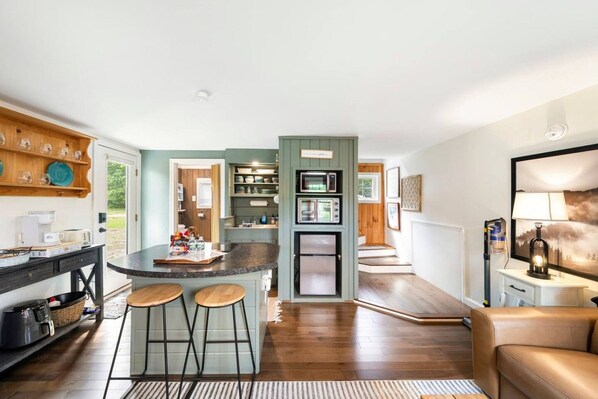 A modern kitchen with a central island, bar stools, and a dining area with a sofa.