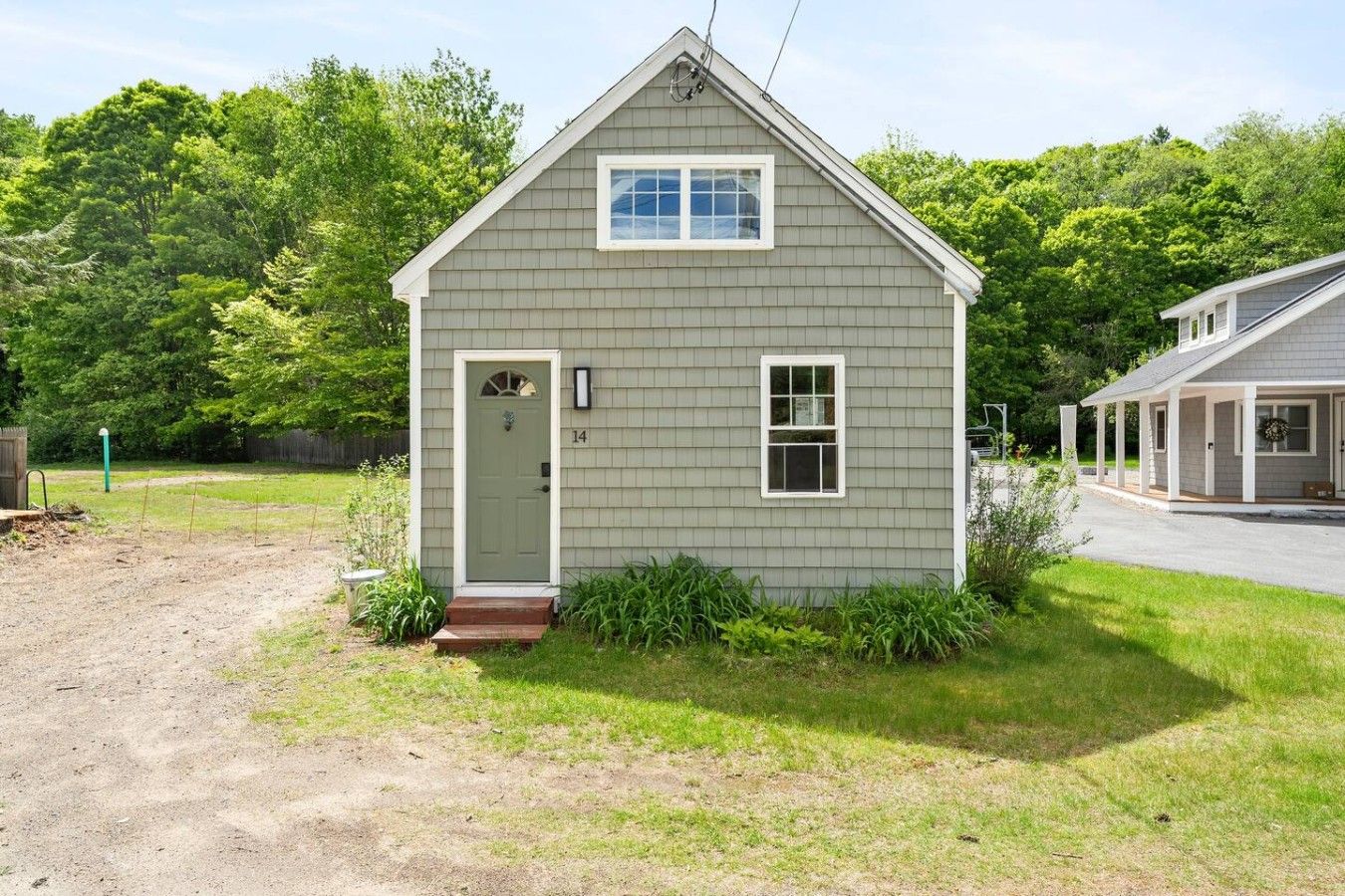 A small, single-story house with a front door, a small porch, and a number '14' on the door.