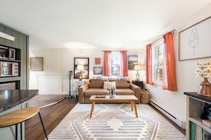 A living room with a sofa, coffee table, and a kitchen area with a microwave.