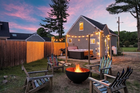 A backyard with a fire pit, wooden chairs, and skis.. White Mtn Hot Tub Retreat The Bit O’ Honey