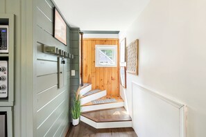 A hallway with a wooden door, a small window, and a staircase leading to another room.