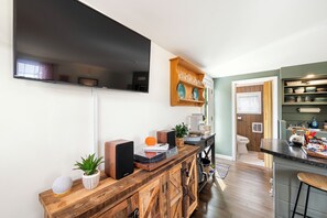 A modern kitchen with a wooden bar, a flat-screen TV, and a dining area with a view.