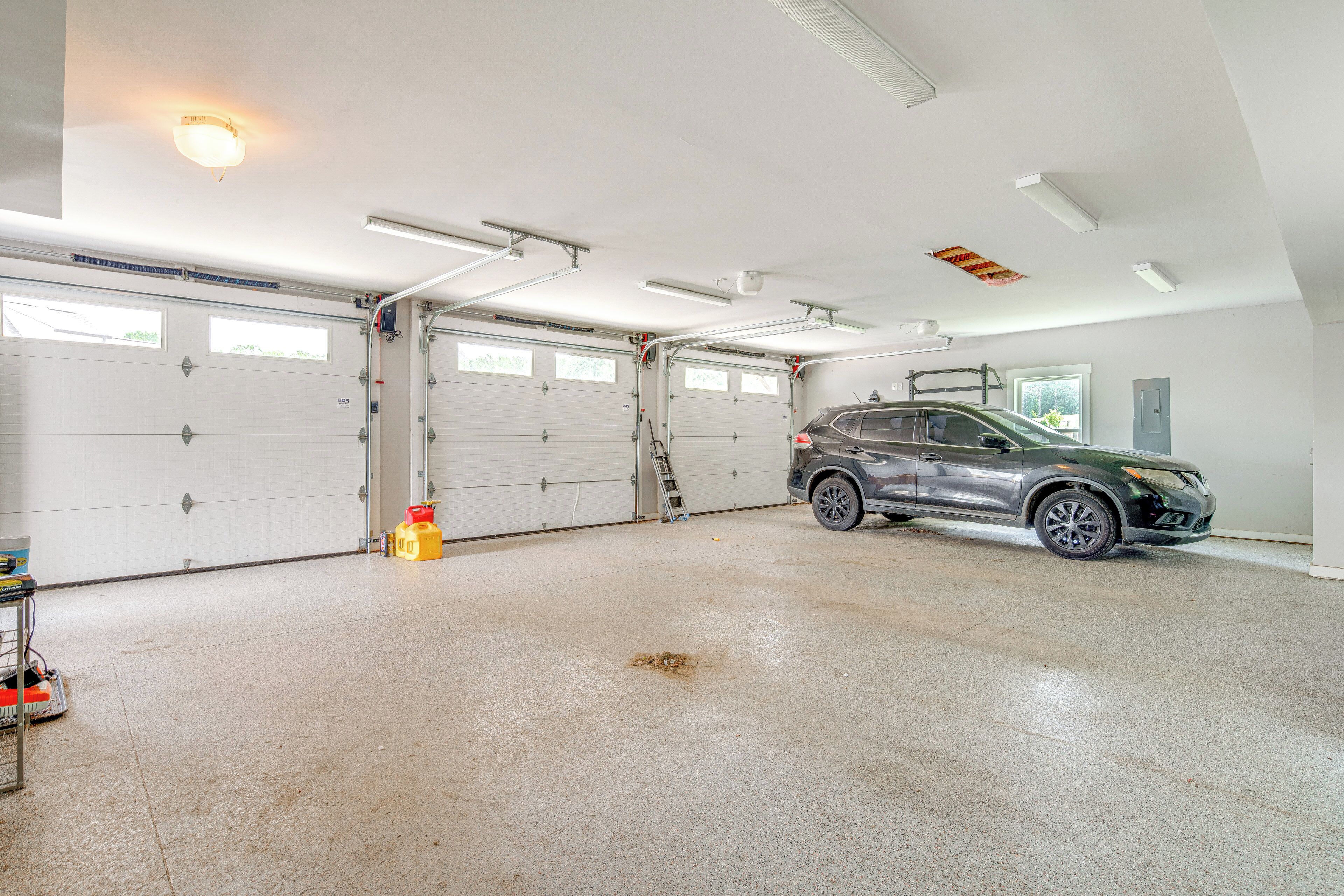 Eine geräumige Garage mit zwei weißen Garagentüren, einer Leiter und einem geparkten SUV.