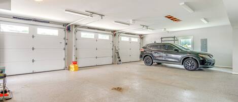 Eine geräumige Garage mit zwei weißen Garagentüren, einer Leiter und einem geparkten SUV.