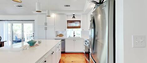 A modern kitchen with white cabinets, a stainless steel refrigerator, and a wooden floor.