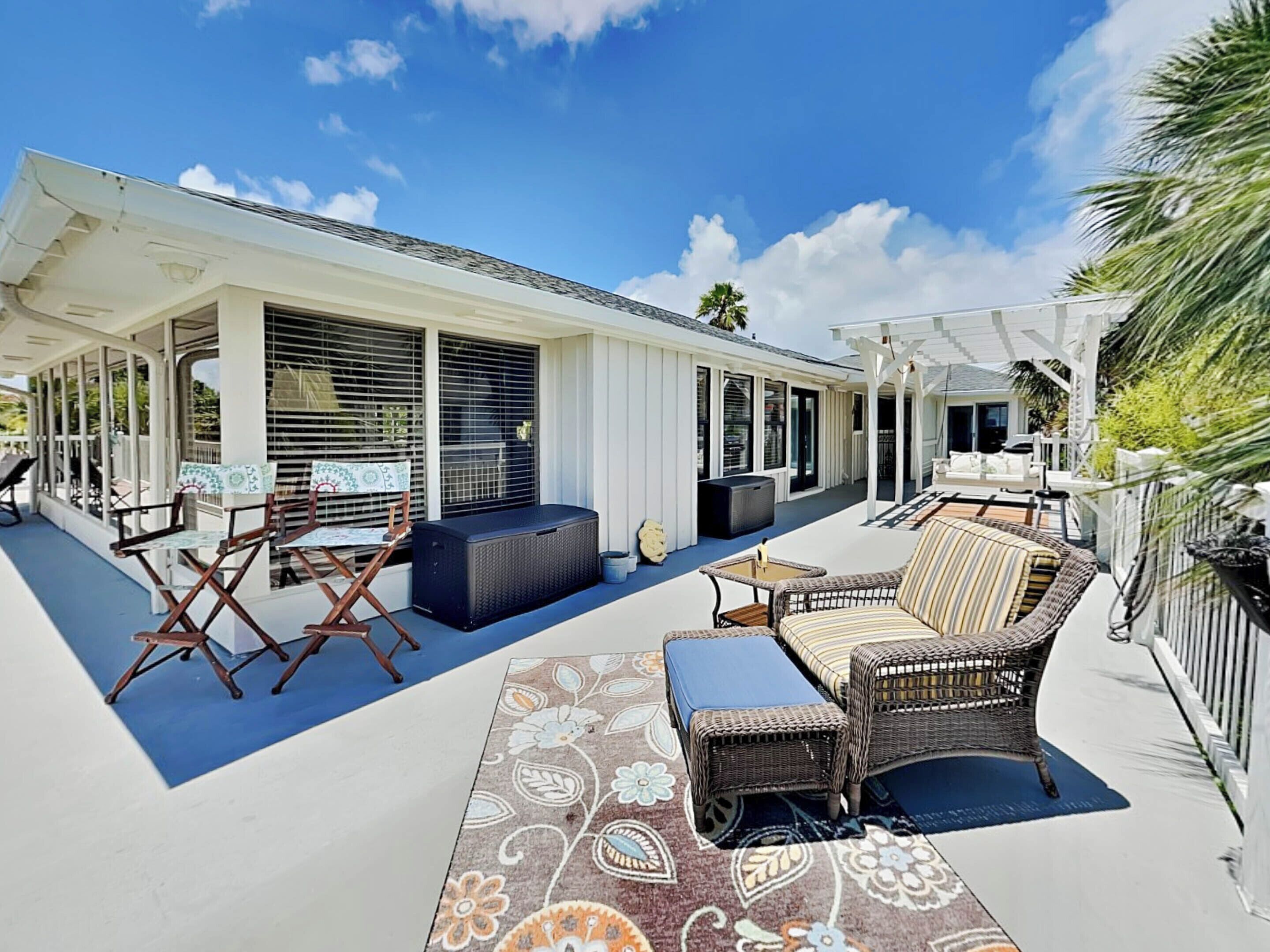 A covered outdoor patio with seating, a large window, and a covered area with a sofa and table.