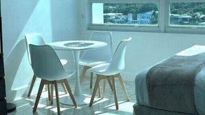 A modern room with a city view, a round table with chairs, and a bed. - Cute Studio Bay view! (Miami)