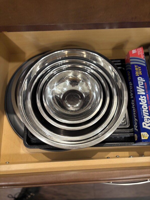 Un cajón con tapas de metal apiladas y una caja de papel de aluminio Reynolds Wrap.