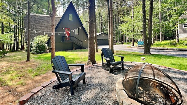 A cabin with a sloped roof, a fire pit, and two Adirondack chairs. - Cooper's Landing by Taylor Made Deep Creek (Swanton)