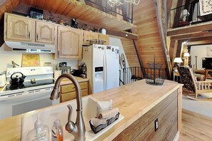 A kitchen with wooden cabinets, a refrigerator, a stove, and a sink. - Cooper's Landing by Taylor Made Deep Creek (Swanton)