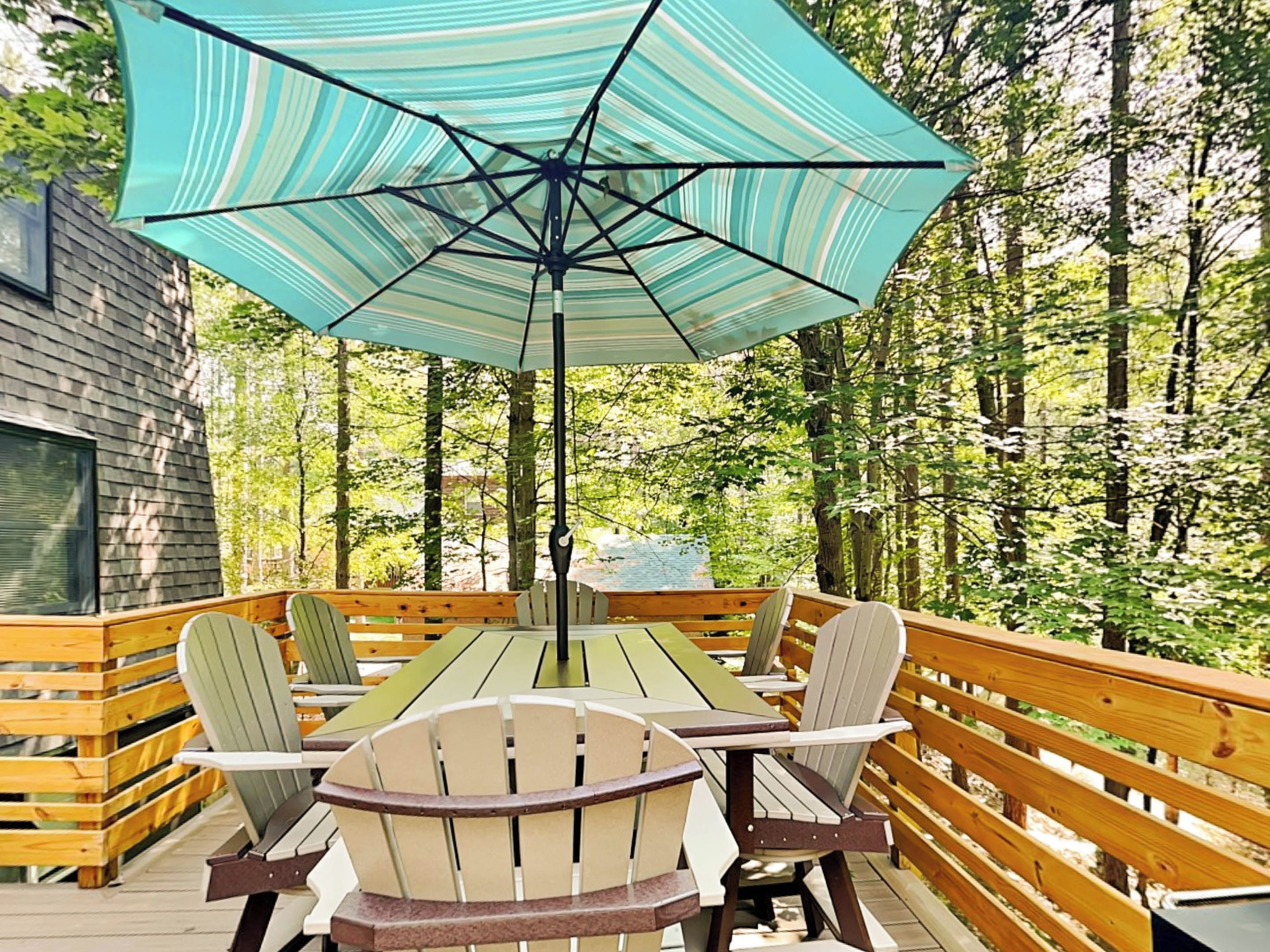 Une terrasse en bois avec une table et des chaises, entourée d’arbres.