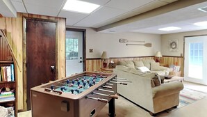 A cozy living room with a foosball table, a sofa, and a bookshelf. - Cooper's Landing by Taylor Made Deep Creek (Swanton)