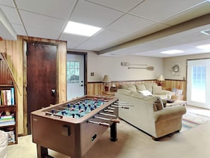 En hyggelig stue med et bordtennisbord, en sofa og en bogreol.
