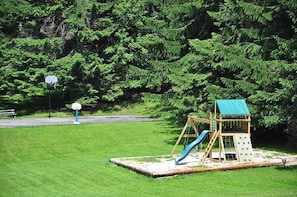 A playground with a slide and climbing wall, surrounded by trees. - Cooper's Landing by Taylor Made Deep Creek (Swanton)