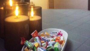 A room with a tiled floor, a wall with a patterned design, and a door. There are two lit candles in glass holders and a bowl of assorted candies. - private room near taxi station and airport 
 (Inezgane)