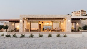 A modern house with a stone facade, outdoor seating area, and a view of the surrounding landscape.