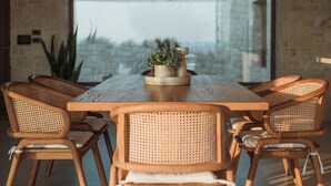 A dining area with a wooden table and six wicker chairs. There is a small potted plant on the table.
