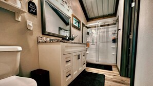 Un baño con inodoro, lavamanos, espejo y ducha.