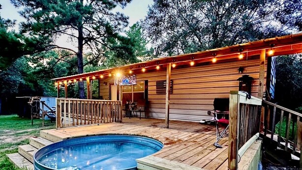 Una terraza de madera con un jacuzzi y un porche cubierto.