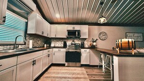Una cocina moderna con gabinetes blancos, una estufa de acero inoxidable y una encimera de madera.