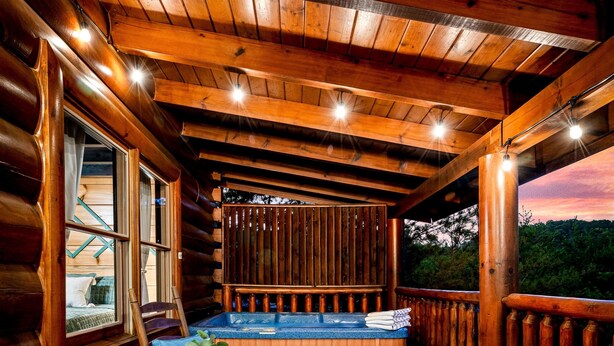 Une cabane en bois avec un bain à remous, une table et des chaises, et une vue sur l’extérieur.