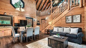 Un intérieur en bois comprenant un coin repas, une cuisine et un escalier menant à un niveau supérieur.