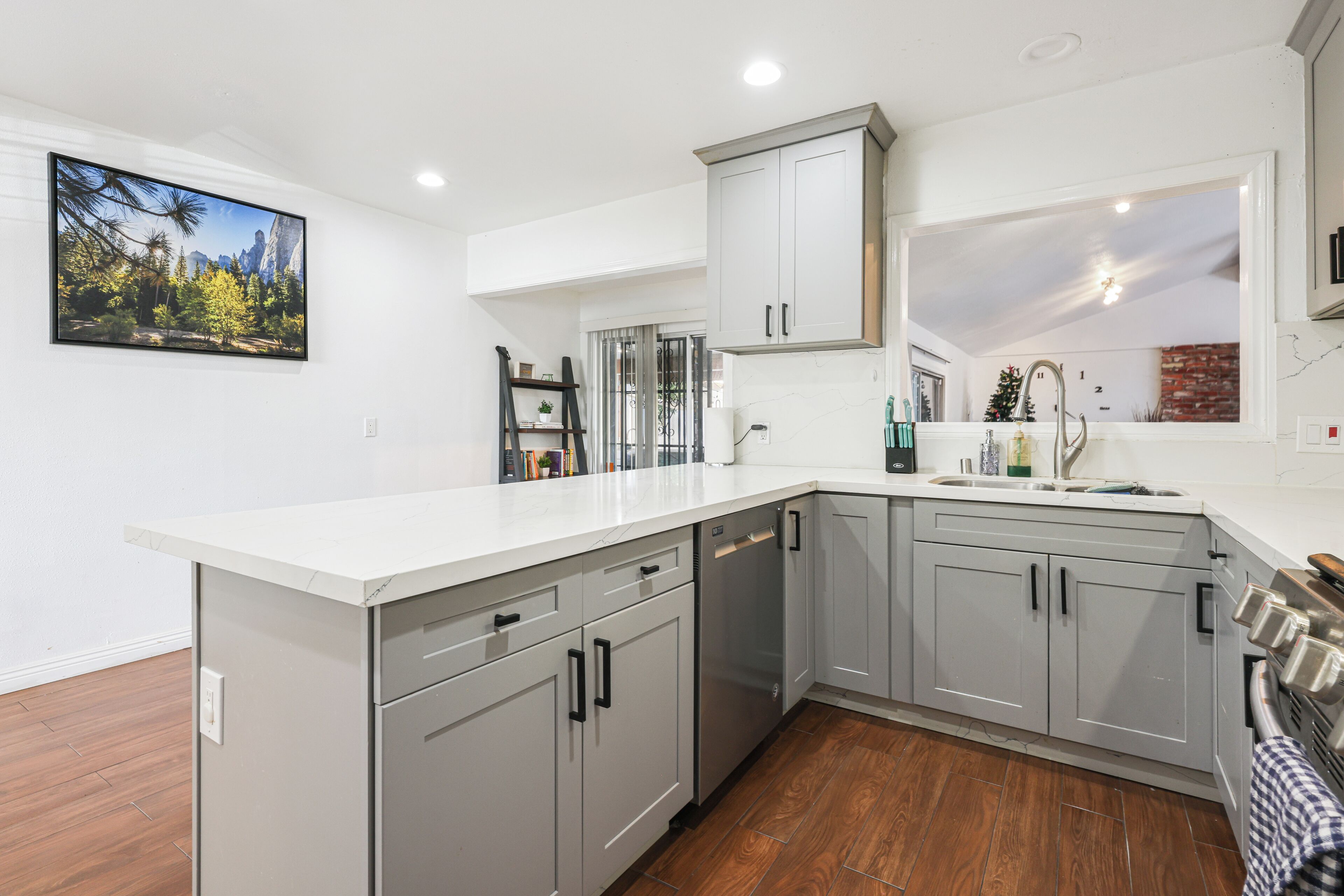 A modern kitchen with grey cabinets, a white countertop, and a built-in dishwasher.