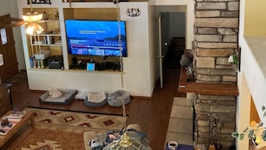 A spacious living room with a television, a stone fireplace, and a cozy seating area. - Roomy Cabin in TALL Pines w/ Fenced Yd, A/C,  4  Bd/2 Ba, 75" TV + 593 movies (Pinetop)