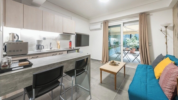 En kompakt bolig med tekøkken, spiseplads og en sofa med puder.
