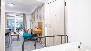 Et hotelværelse med en seng, et skrivebord med stol, en blå sofa, et træskab og udsigt til det fri.
