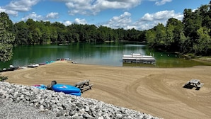 Zona junto al lago con un muelle, mesas de picnic y balsas inflables.