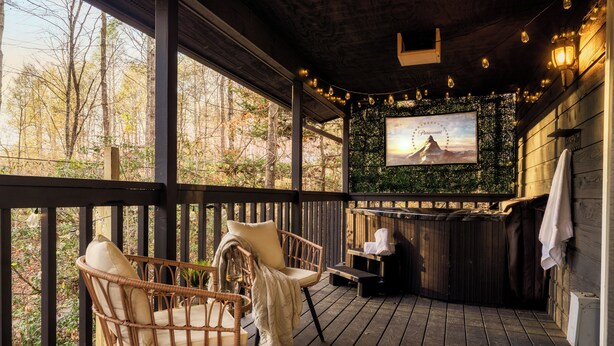 A wooden deck with wicker chairs, a bench, and a hot tub. - Romantic cabin with Sauna, fitness room in Gatlinburg, near NP, Pet-Friendly (Gatlinburg)
