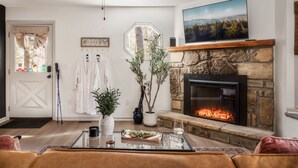 A living room with a stone fireplace, a television mounted above it, and a cozy seating area with a coffee table. - Romantic cabin with Sauna, fitness room in Gatlinburg, near NP, Pet-Friendly (Gatlinburg)