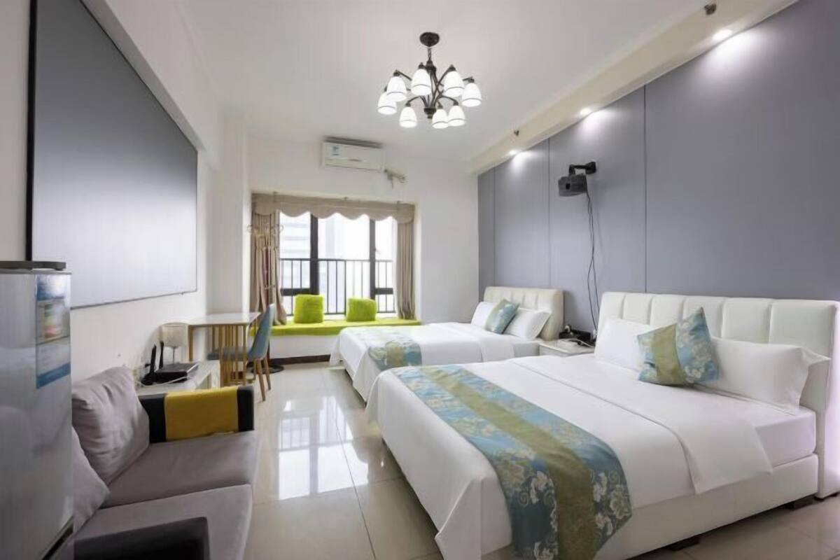 Habitación de hotel con dos camas, un sofá, un escritorio y una ventana con cortinas.