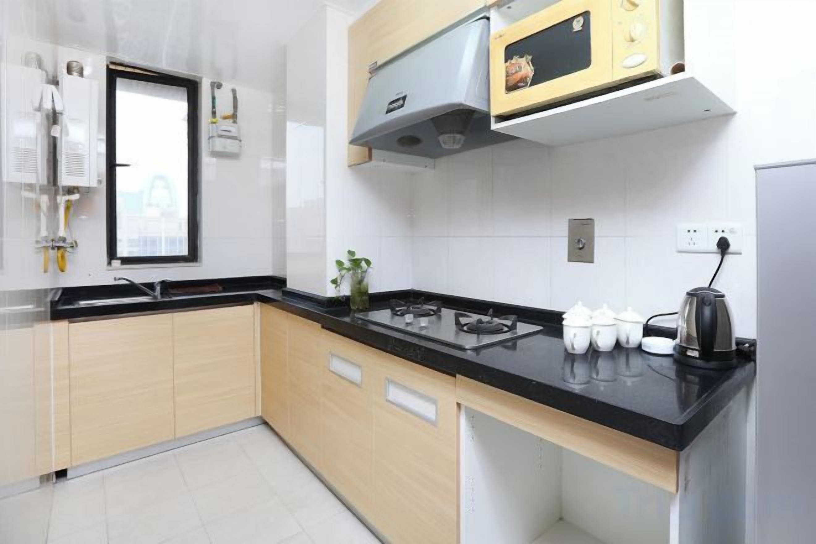 A kitchen with a black countertop, wooden cabinets, a microwave, and a stove.