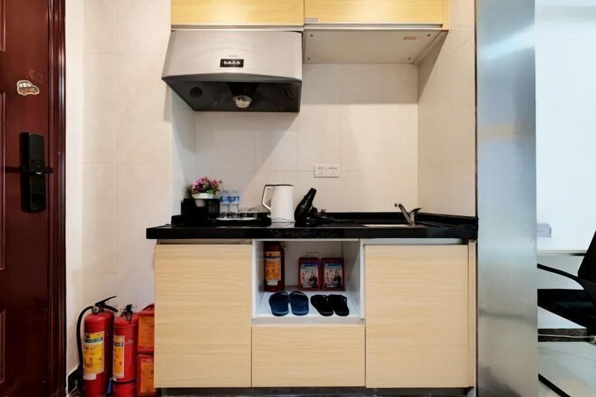 A compact kitchen with a black countertop, a white wall, and a wooden cabinet below.