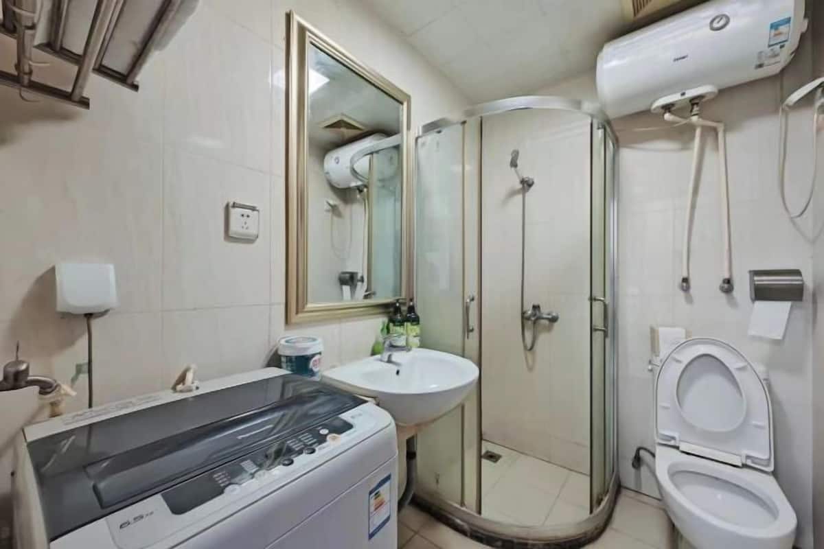 Un baño con lavadora, lavabo, inodoro y ducha con mampara de vidrio.