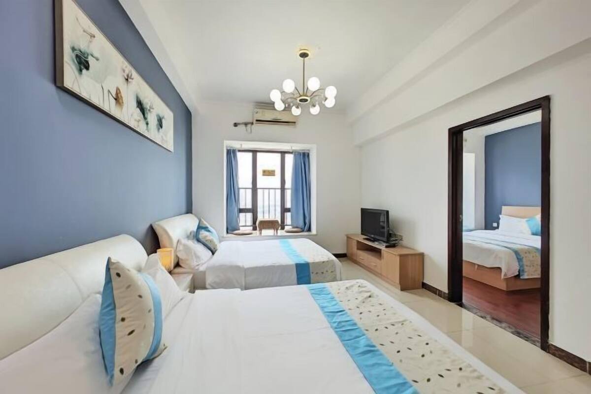 Habitación de hotel con dos camas, televisión, escritorio y espejo.