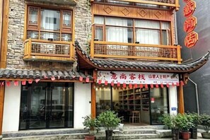 Un bâtiment traditionnel avec un toit en tuiles, des balcons en bois et une enseigne ornée de caractères chinois.