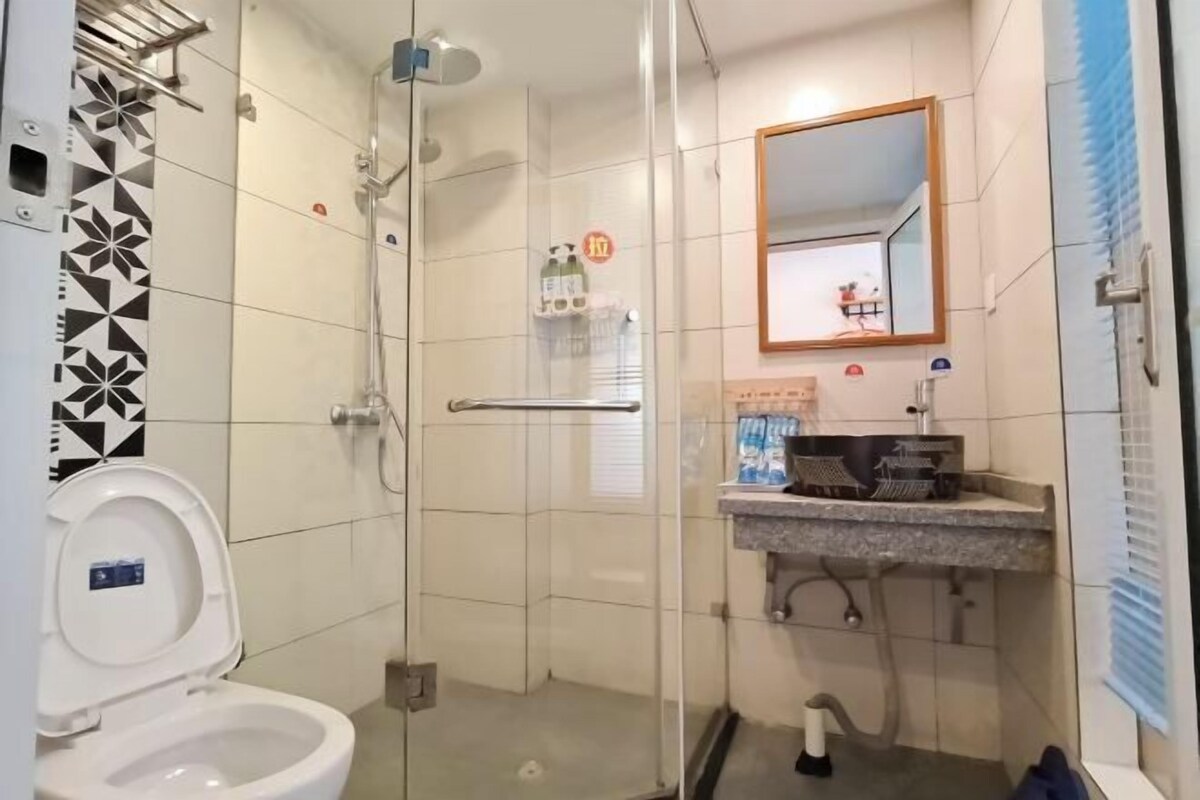 A bathroom with a toilet, a glass-enclosed shower, a sink with a mirror, and a towel rack.