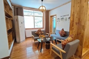 Un salon confortable avec un canapé, des fauteuils, une table et une fenêtre.